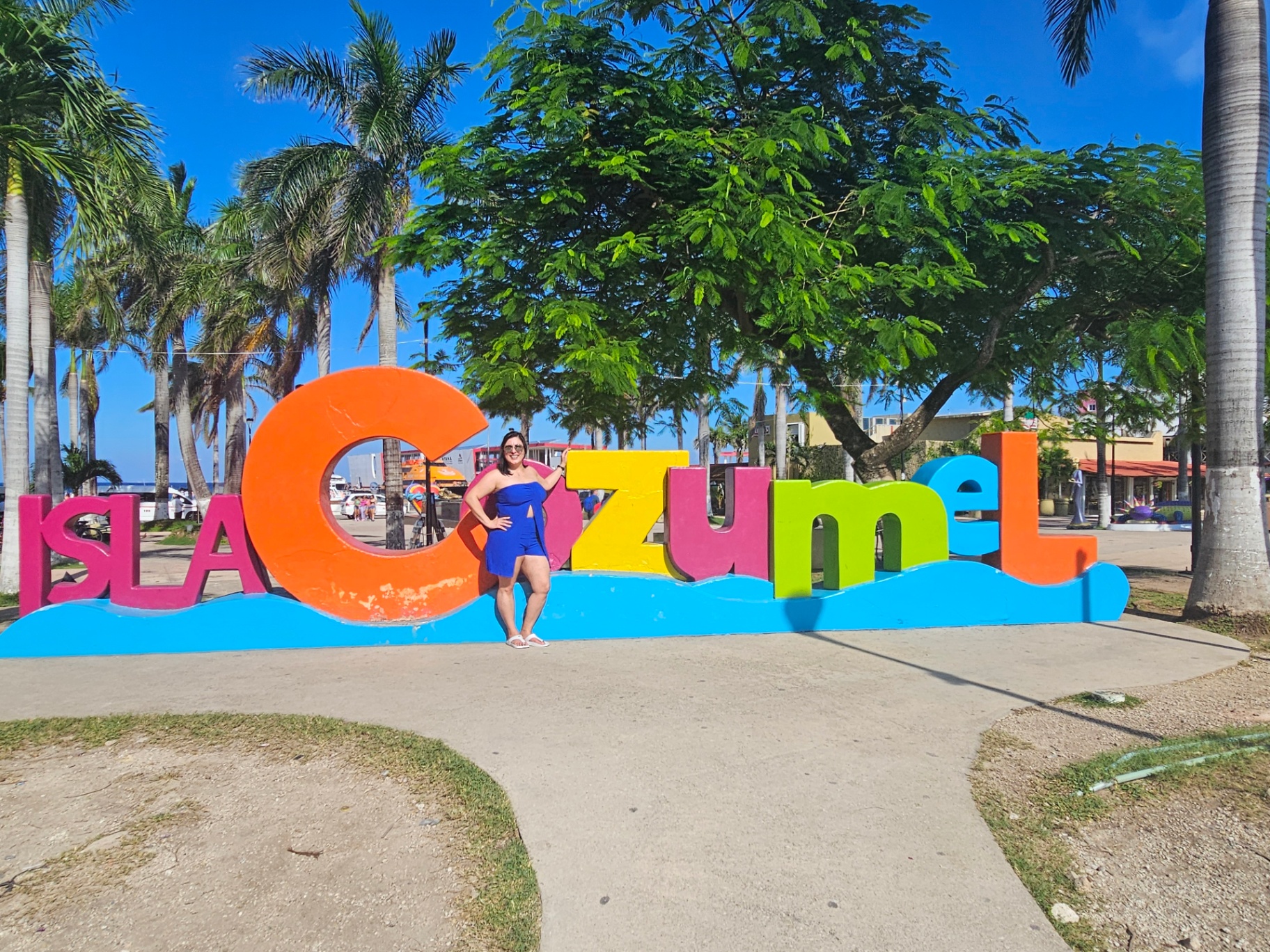 Woman standing by the colorful Isla Cozumel sign