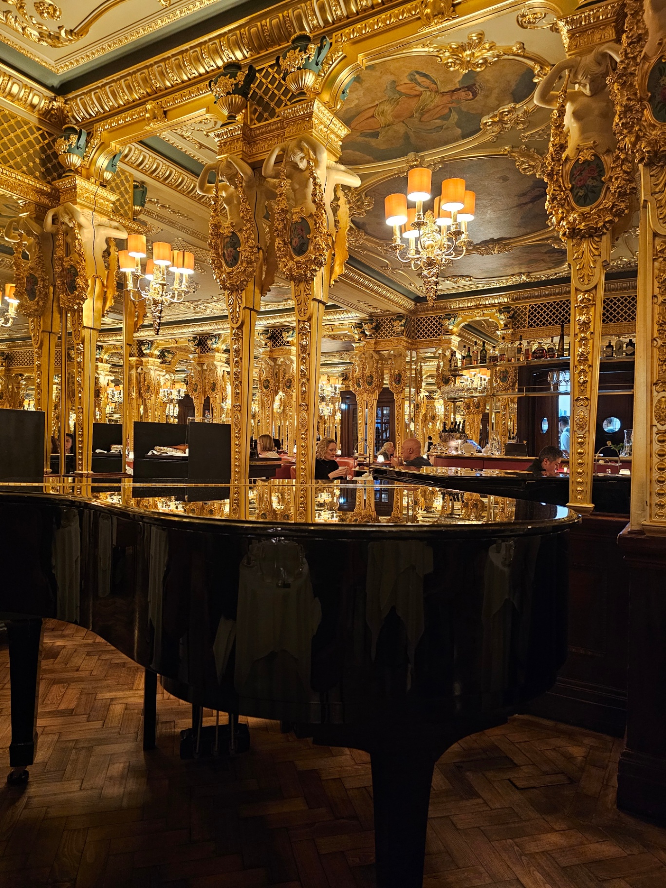 Black grand piano in an ornate golden dining room