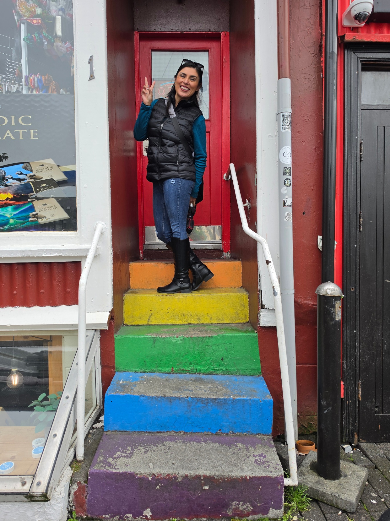 Woman on rainbow-painted steps outside a Reykjavík shop