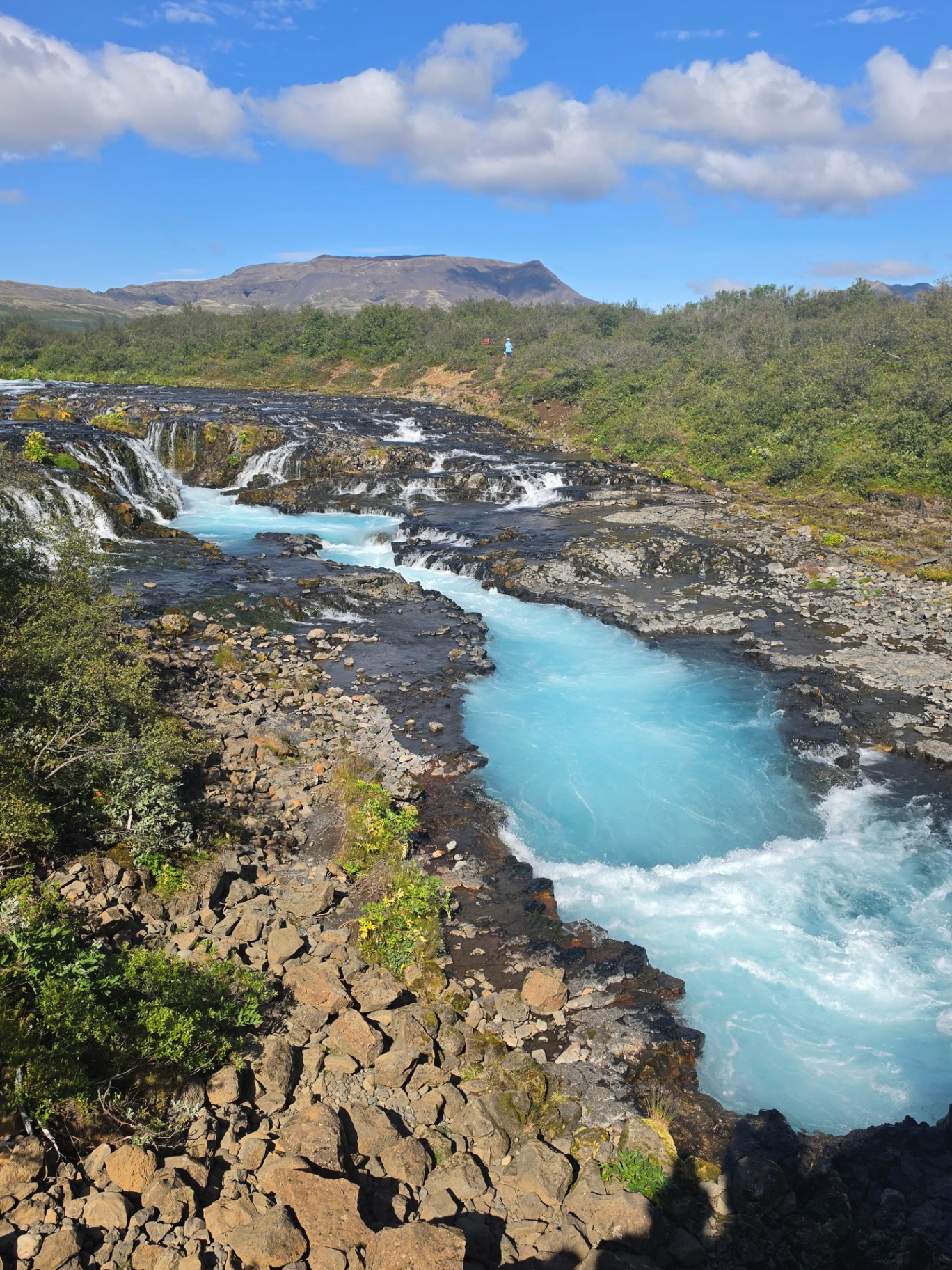 Bright turquoise water tumbling over lava rock at Brúarfoss