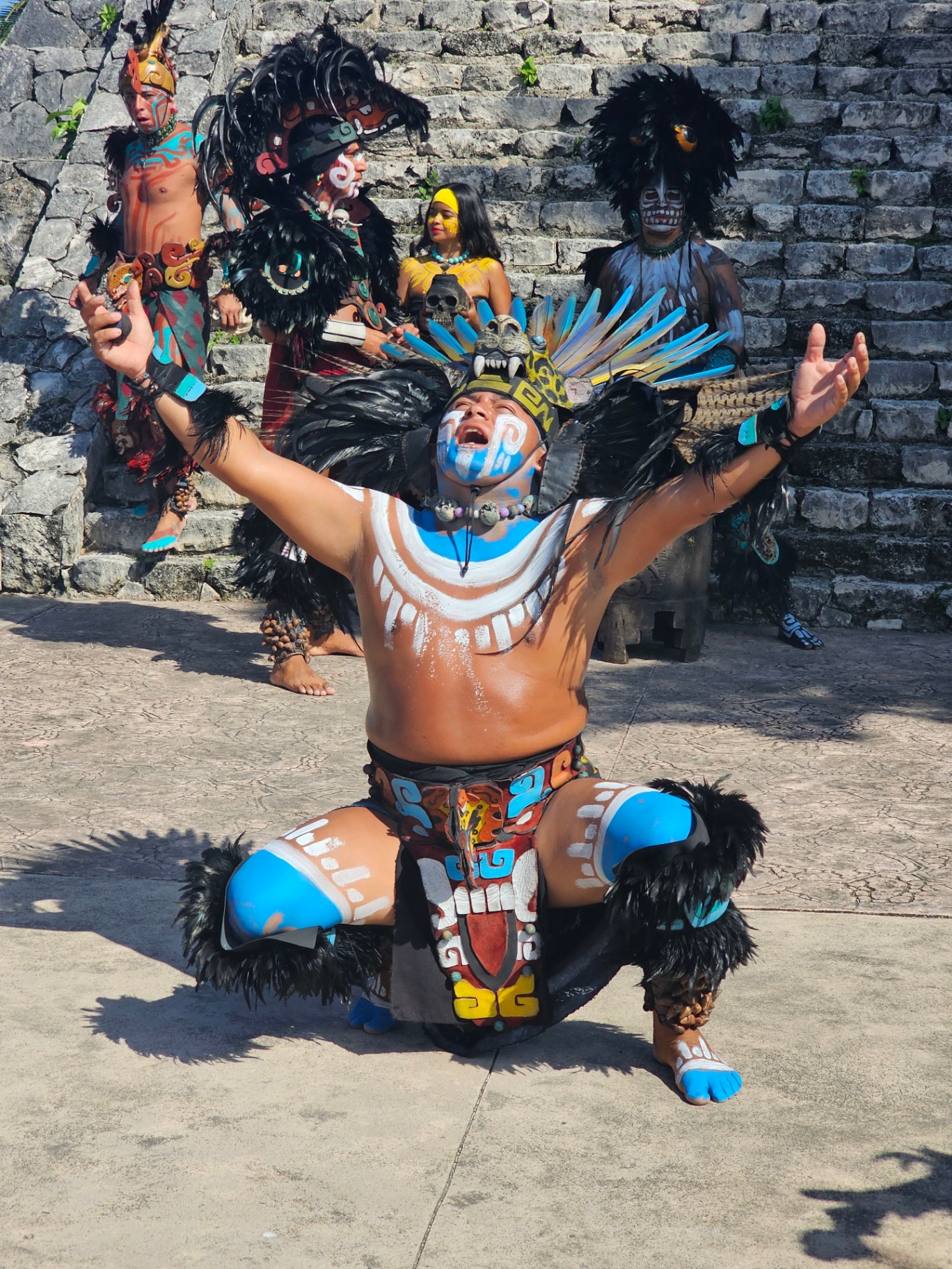Mayan dancer kneeling with arms raised before stone steps